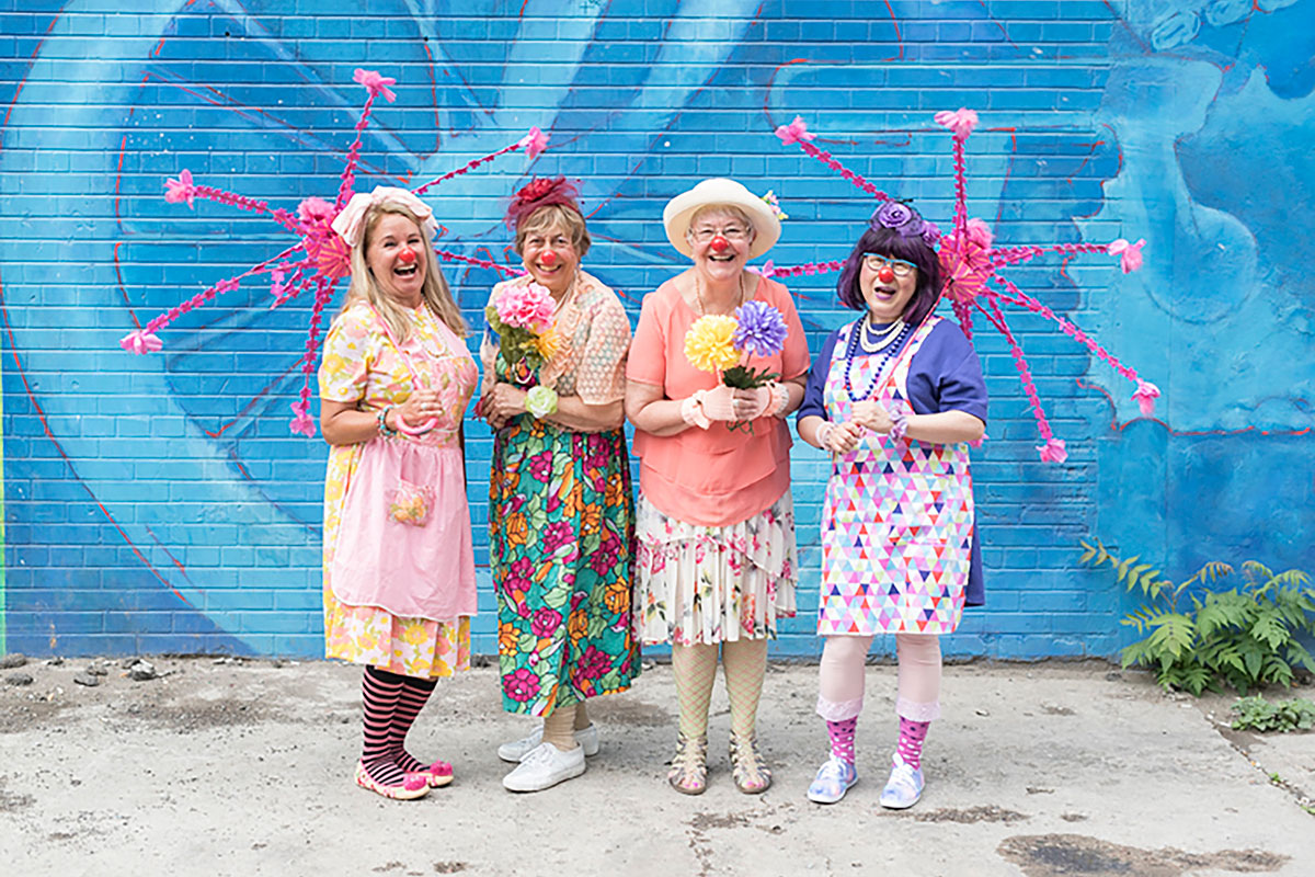 Four smiling students in their caring clown costumes