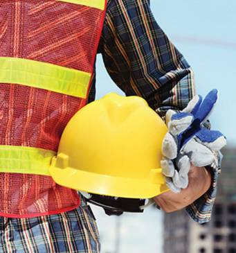 a construction worker holding a yellow helmet in front of a construction site