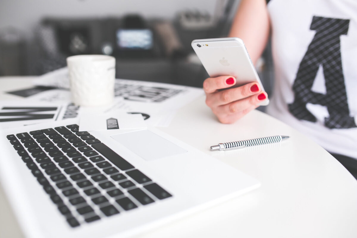 person sitting at desk with laptop and on their mobile phone