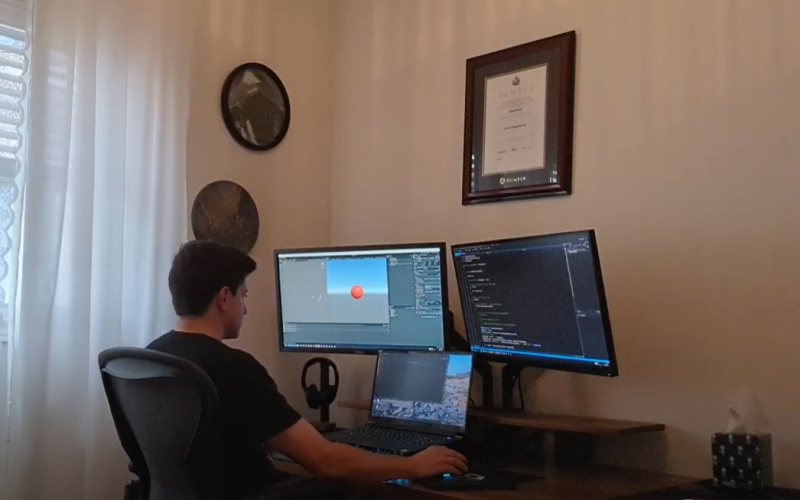 Dylan in front of his dual monitor set-up troubleshooting a Unity project