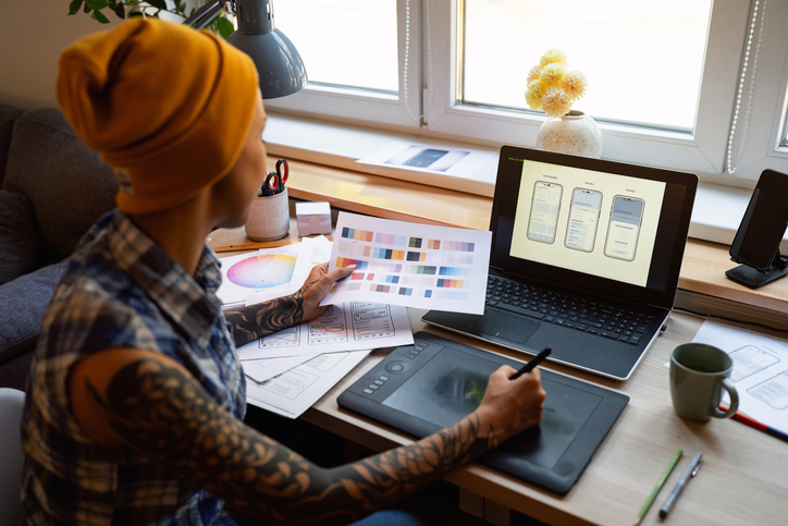 Designer working at a computer and tablet creating digital mockups