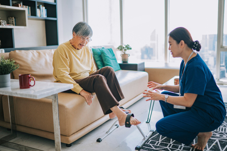 Female physiologist home caregiver encouraging senior woman to exercise