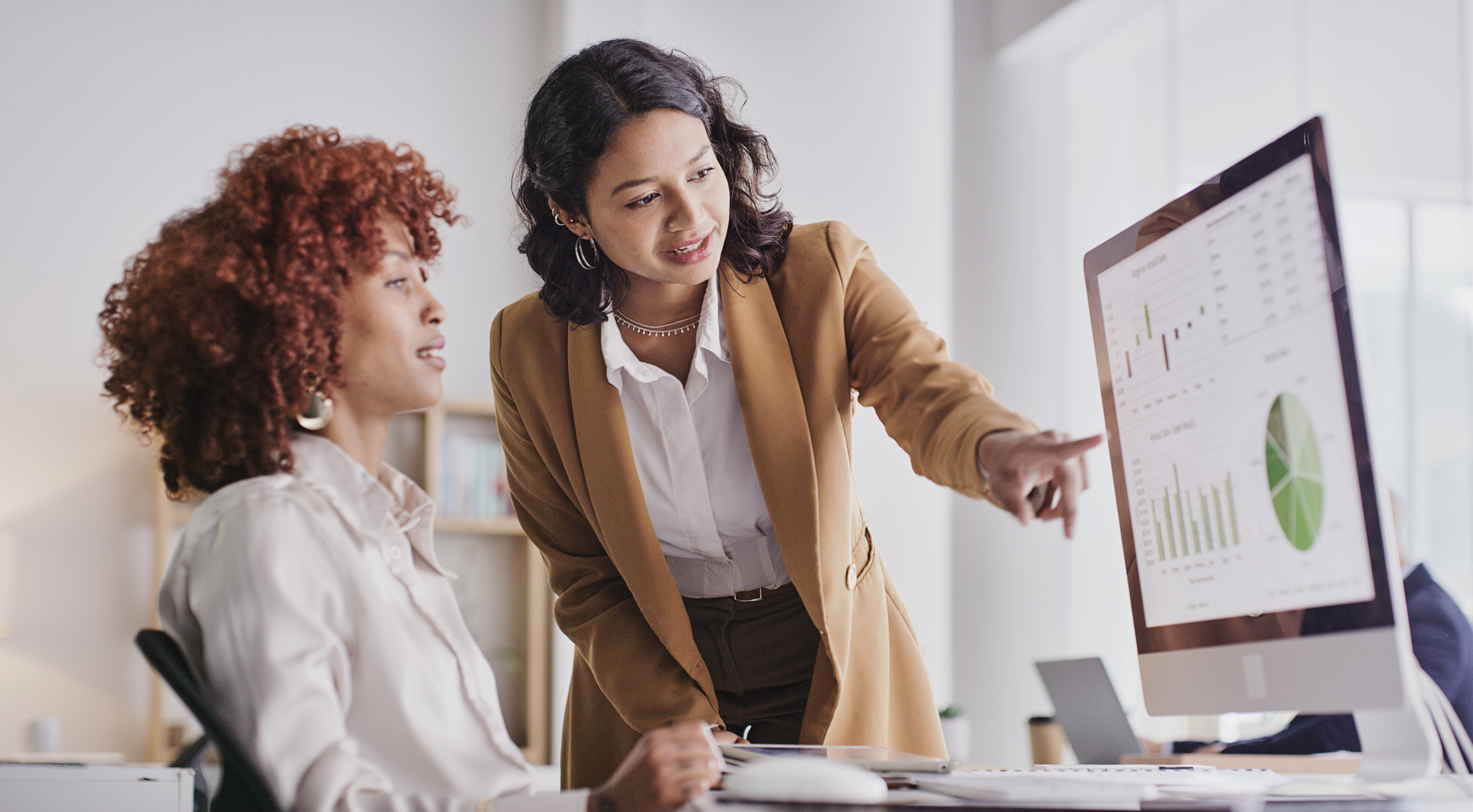 Two women meeting together to review and update finance documents.