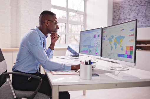 Man working at a desktop with data dashboards