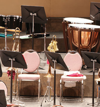 musical instruments including drums, brass instruments, and music stands in a music room