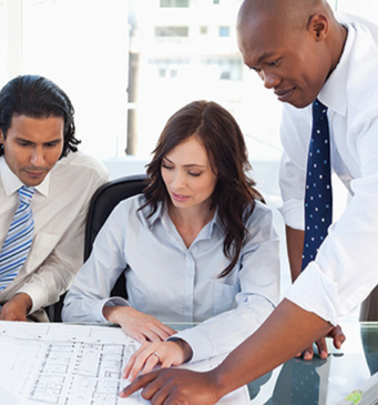 a team of professional men and women in a meeting room viewing a printed diagram