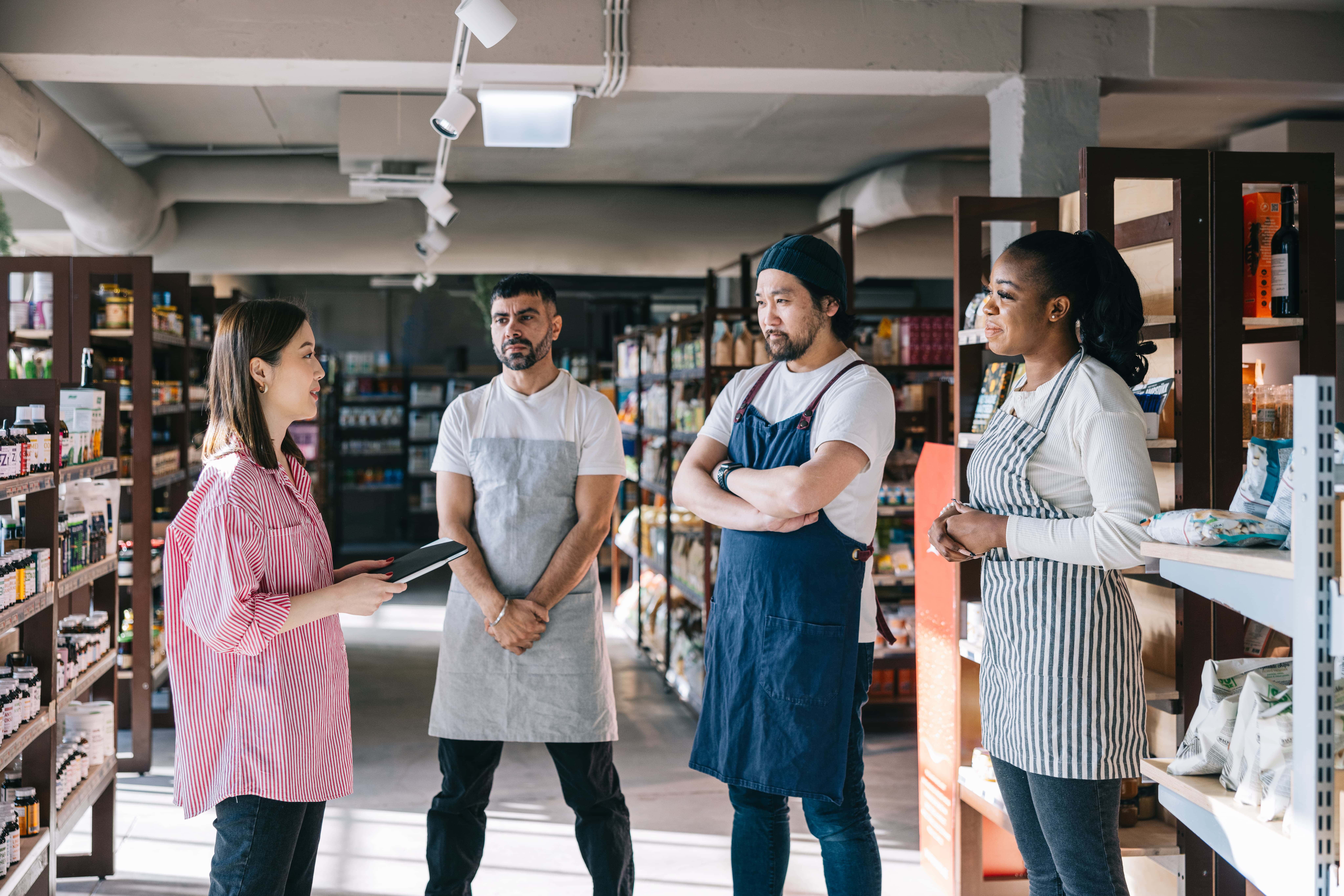 Shop management having a chat with her employees at convenience store