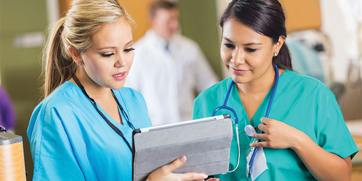 two female nurses in a hospital consulting an iPad
